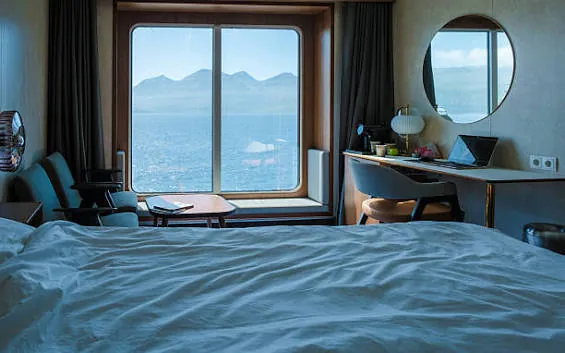 Crew cabin with a bed, desk and window overlooking the sea