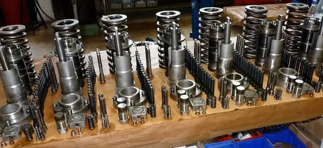 Rows of machined engine spare parts laid out on a workbench