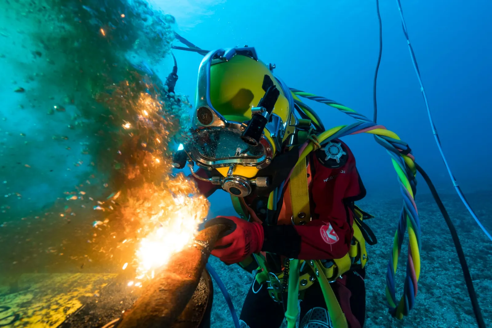 Diver welding underwater, with sparks from the welding arc